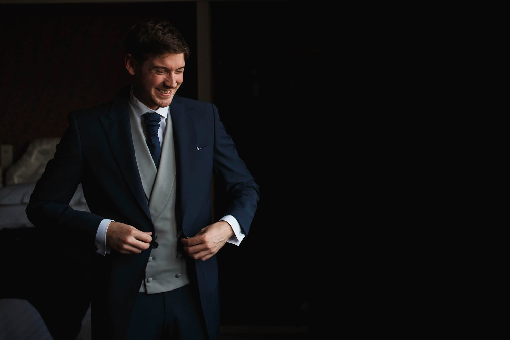 Groom getting ready putting blazer on wedding