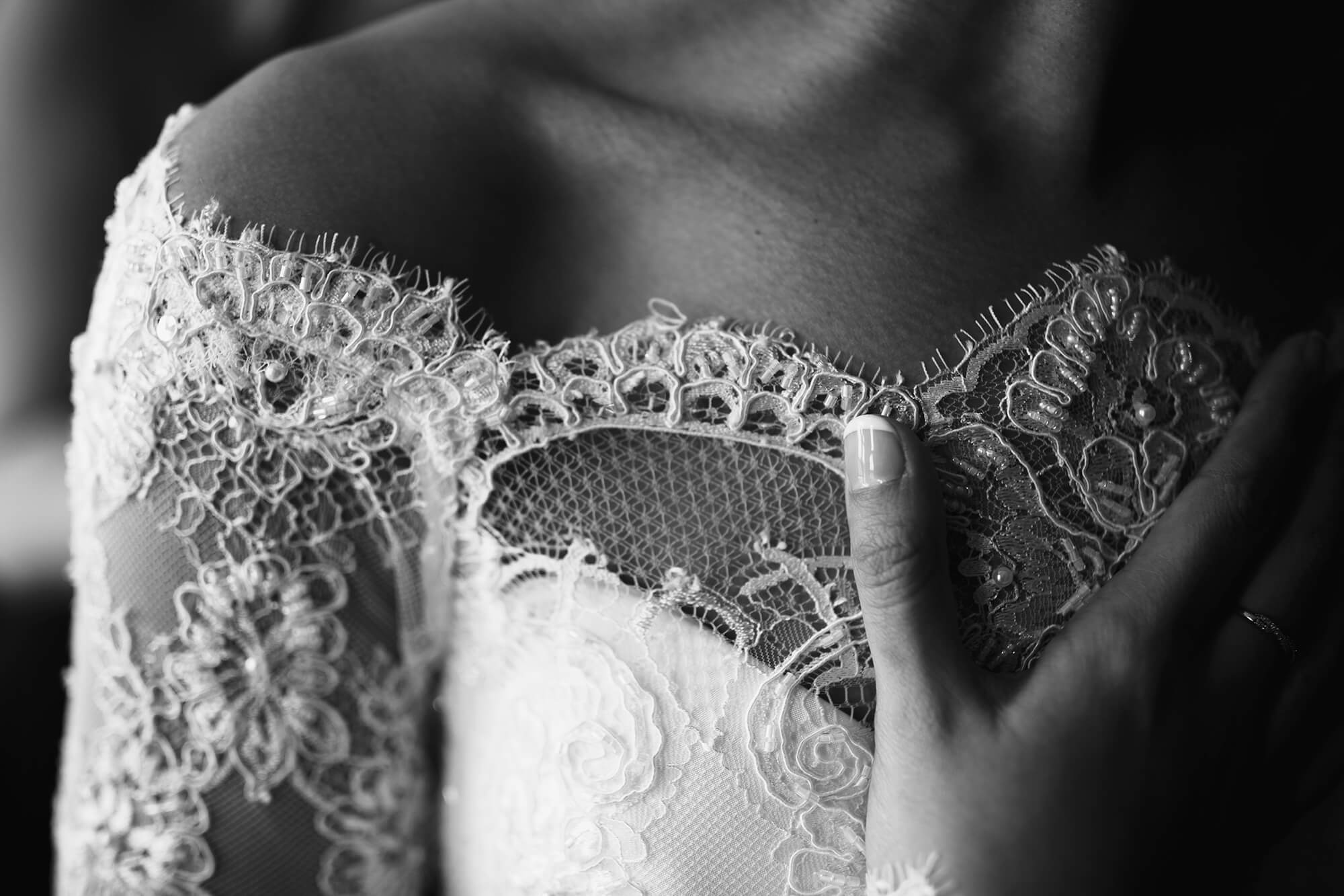 Close up of brides dress with hand on chest black and white effect Thornton
