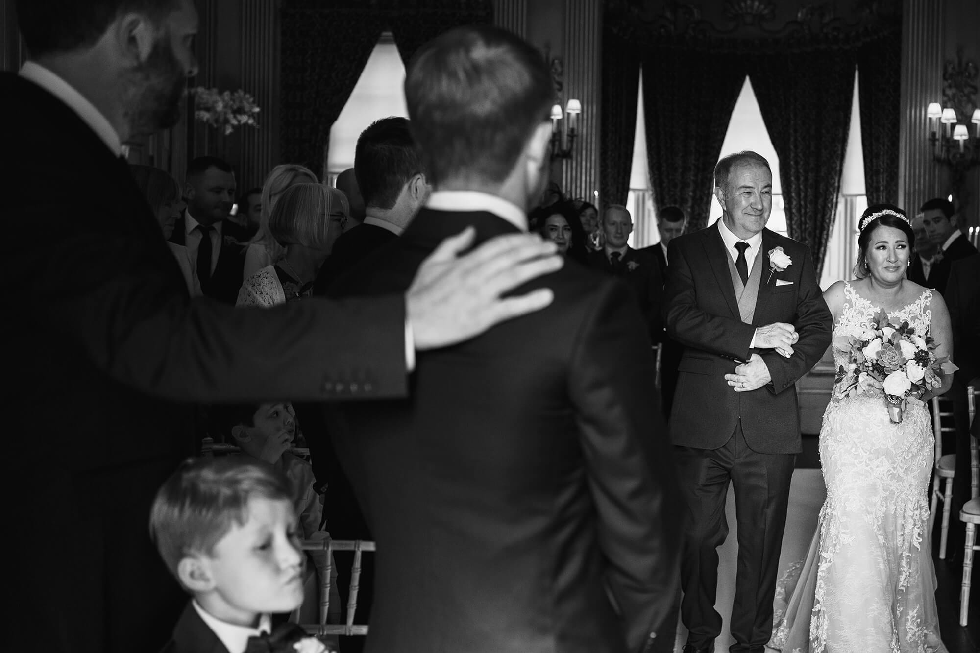 bride walks down isle with dad at Knowsley Hall