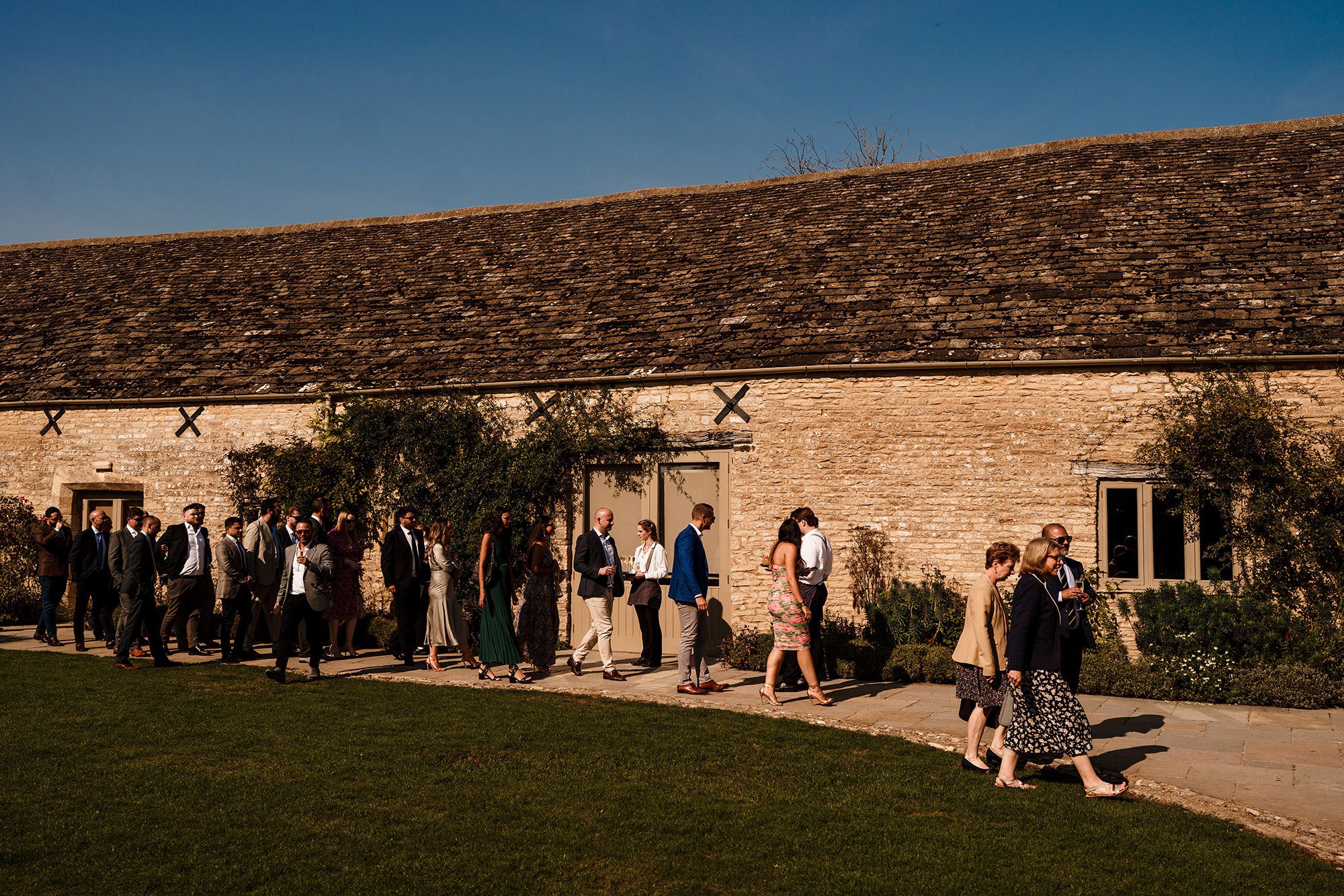 Caswell House wedding guests walk along stone  wall