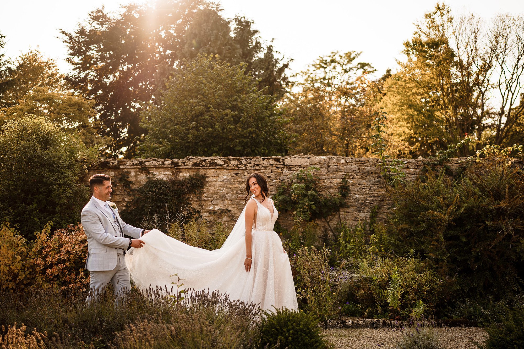 Groom holding brides dress at Caswell House in The Cotswolds