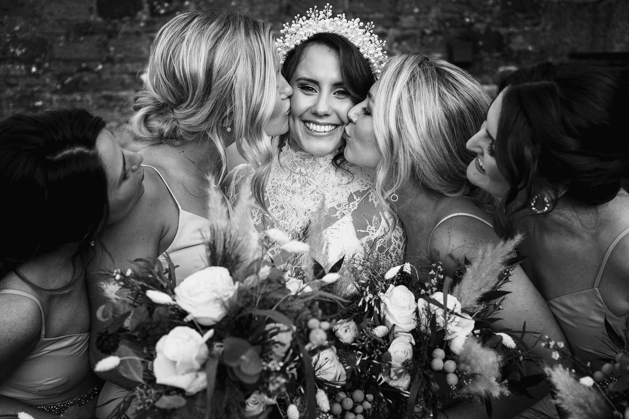 bridesmaids kiss bride surrounded by Lake District flowers