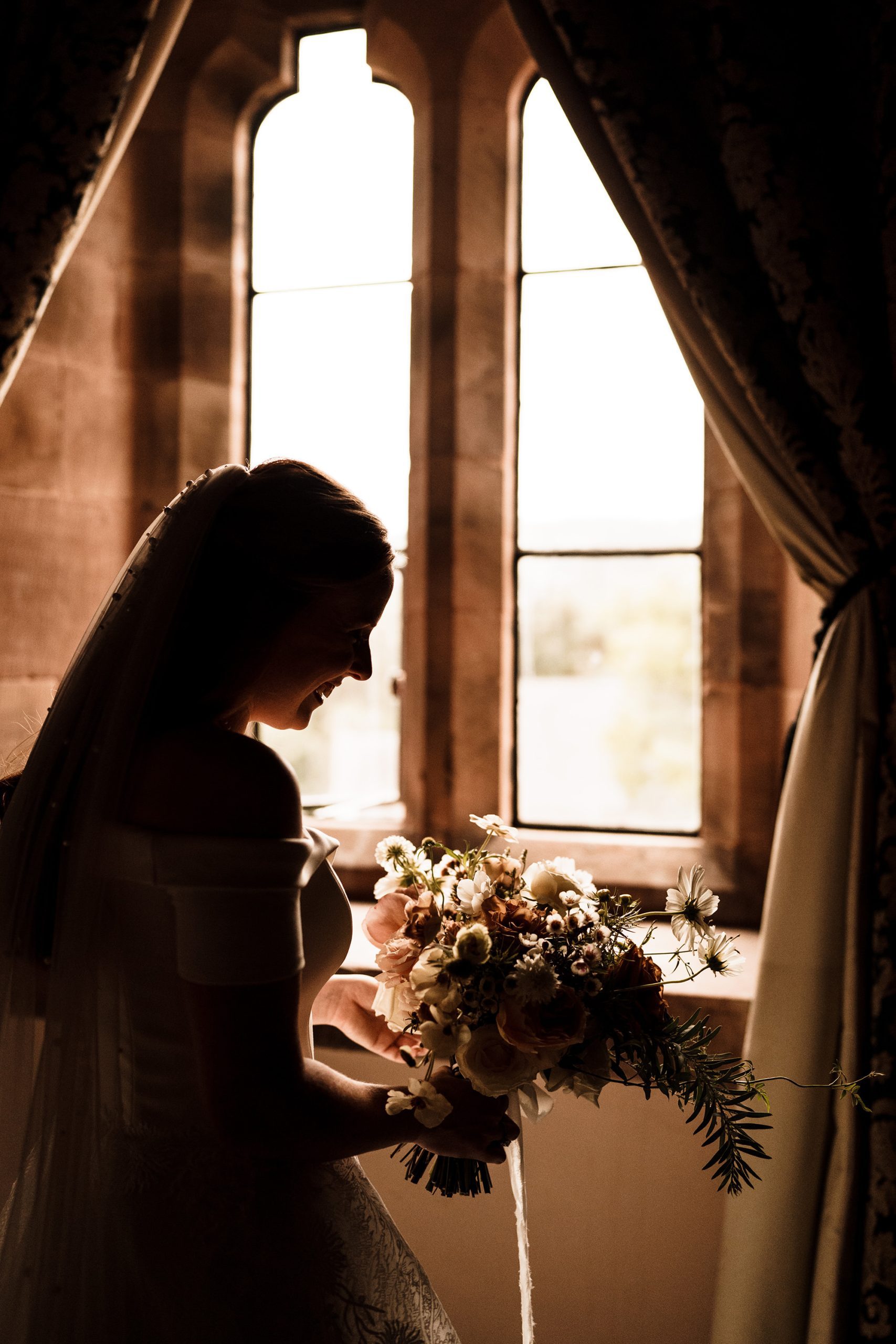 bride looking at flowers in front of window in Cheshire