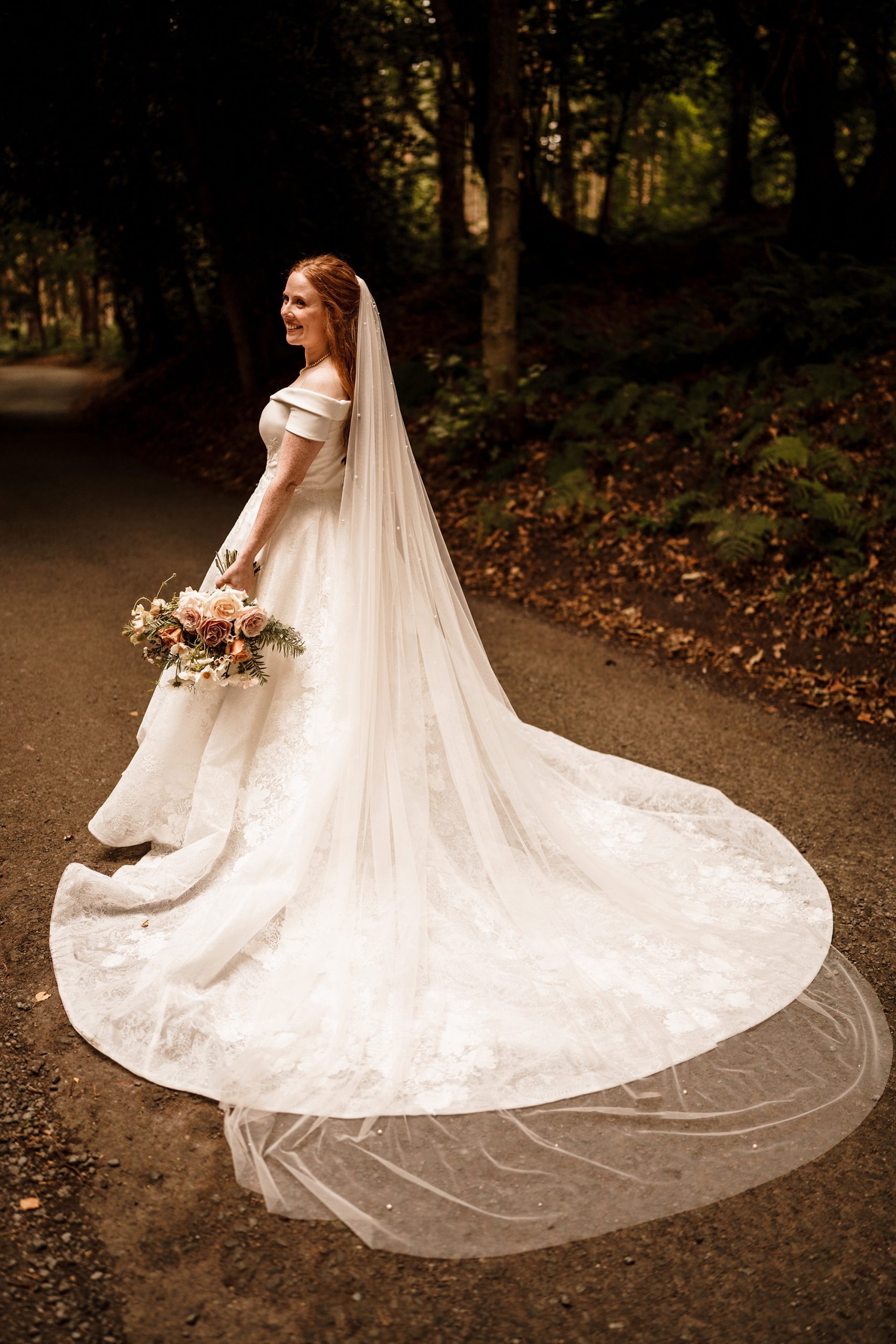 bride poses for photo on the grounds of Peckforton Castle