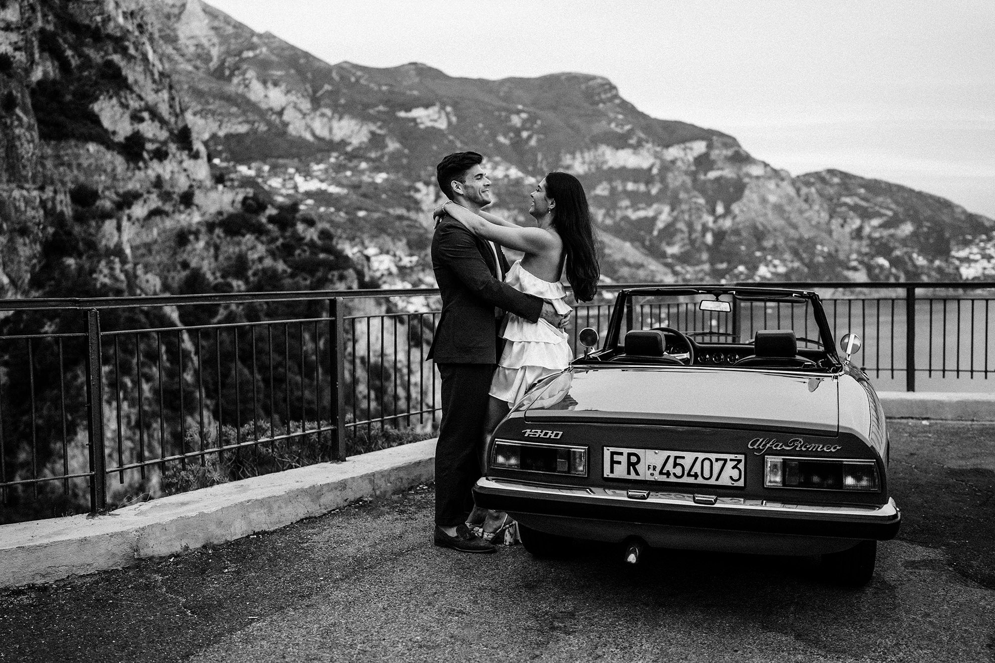 couple posing by car on coastal road on amalfi coast