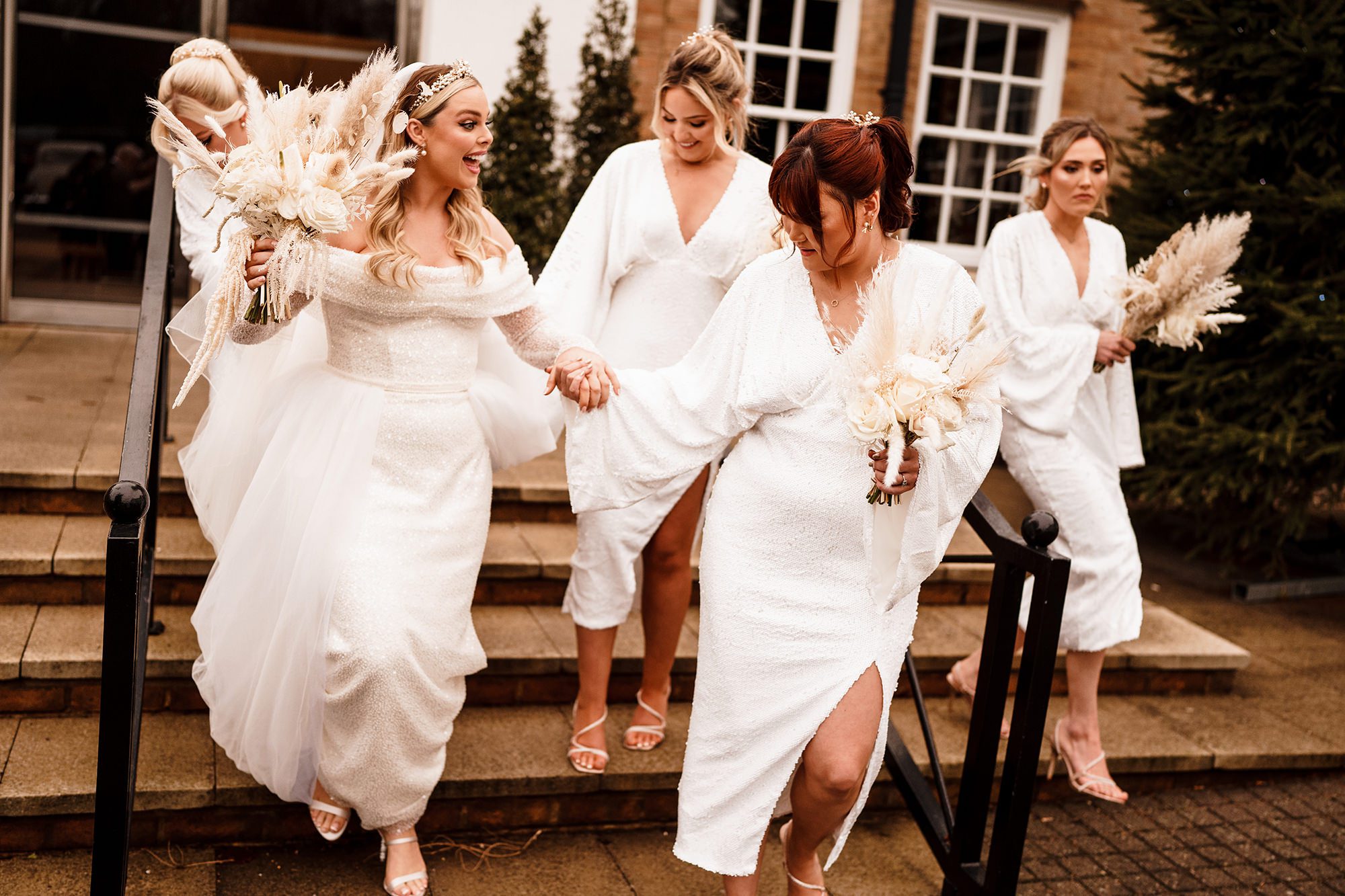 bridemaids holding brides hand walking down steps