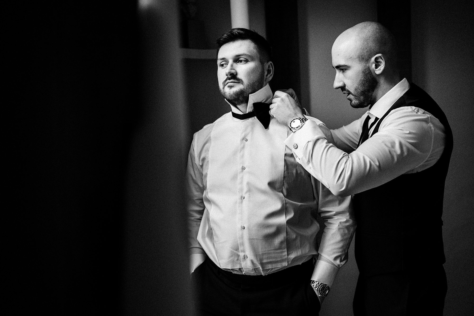 groomsman fastens grooms bow tie at Suffolk wedding