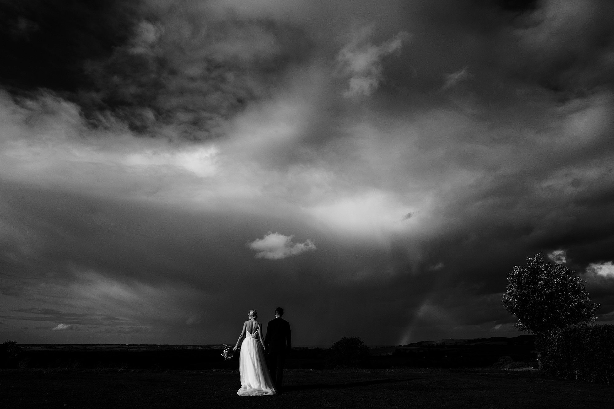 bride and groom walking towards a storm in black and white scene