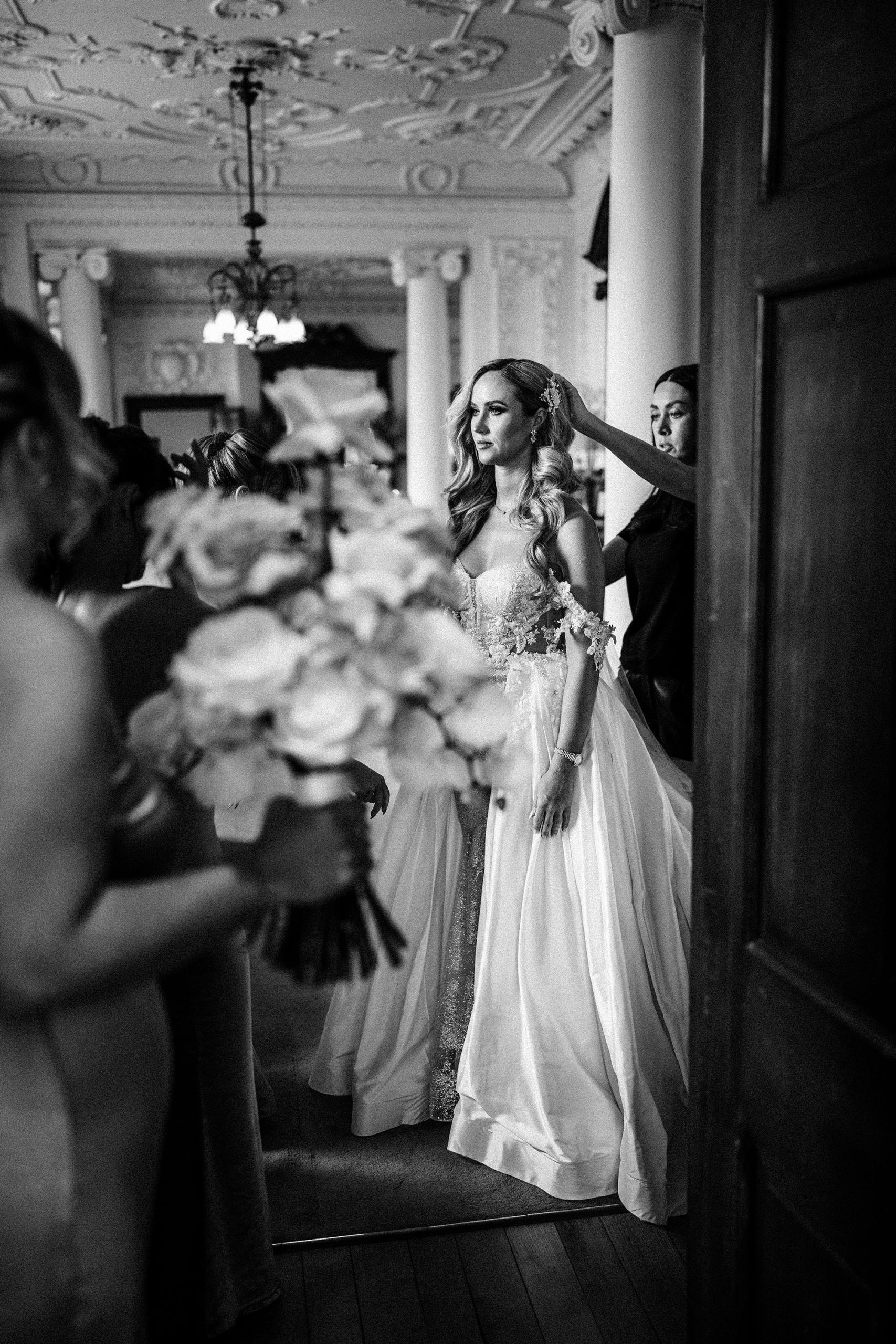 hairdresser adjusting bride before luxury wedding ceremony at Hawkstone Hall