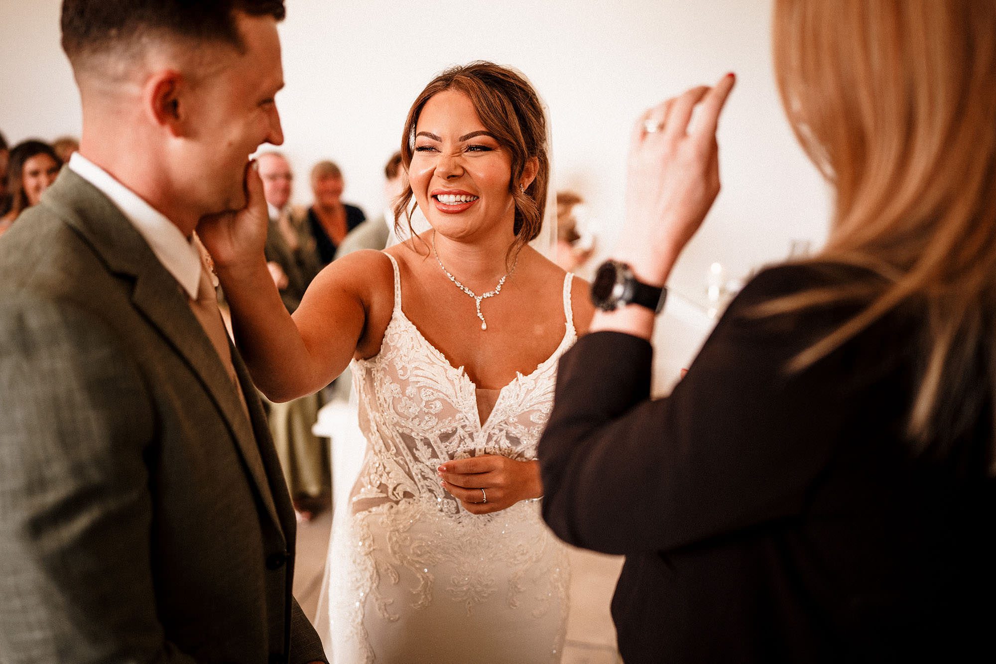 bride wipes lipstick from grooms face during wedding ceremony.