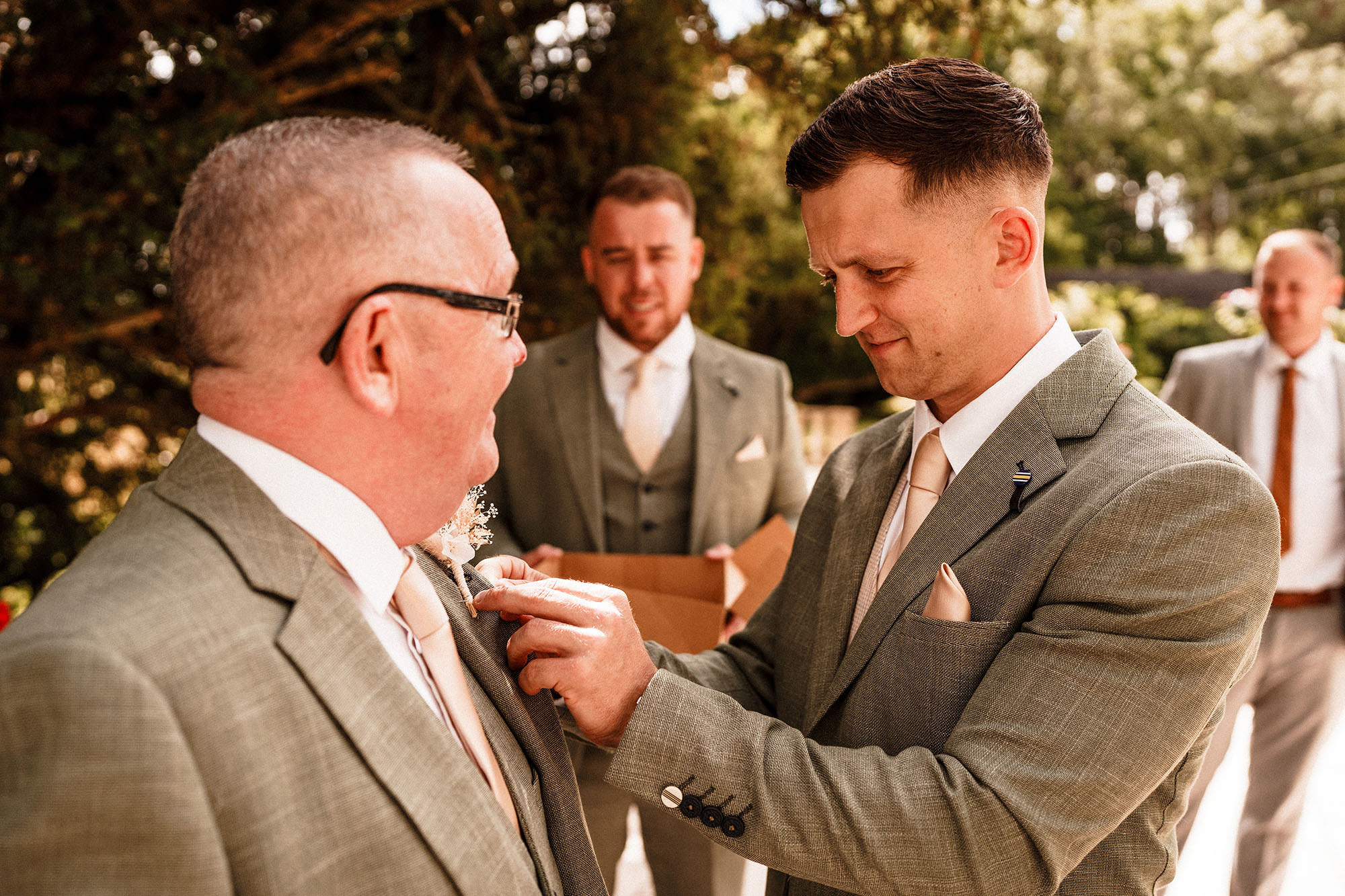 groom attaching buttonhole to groomsman