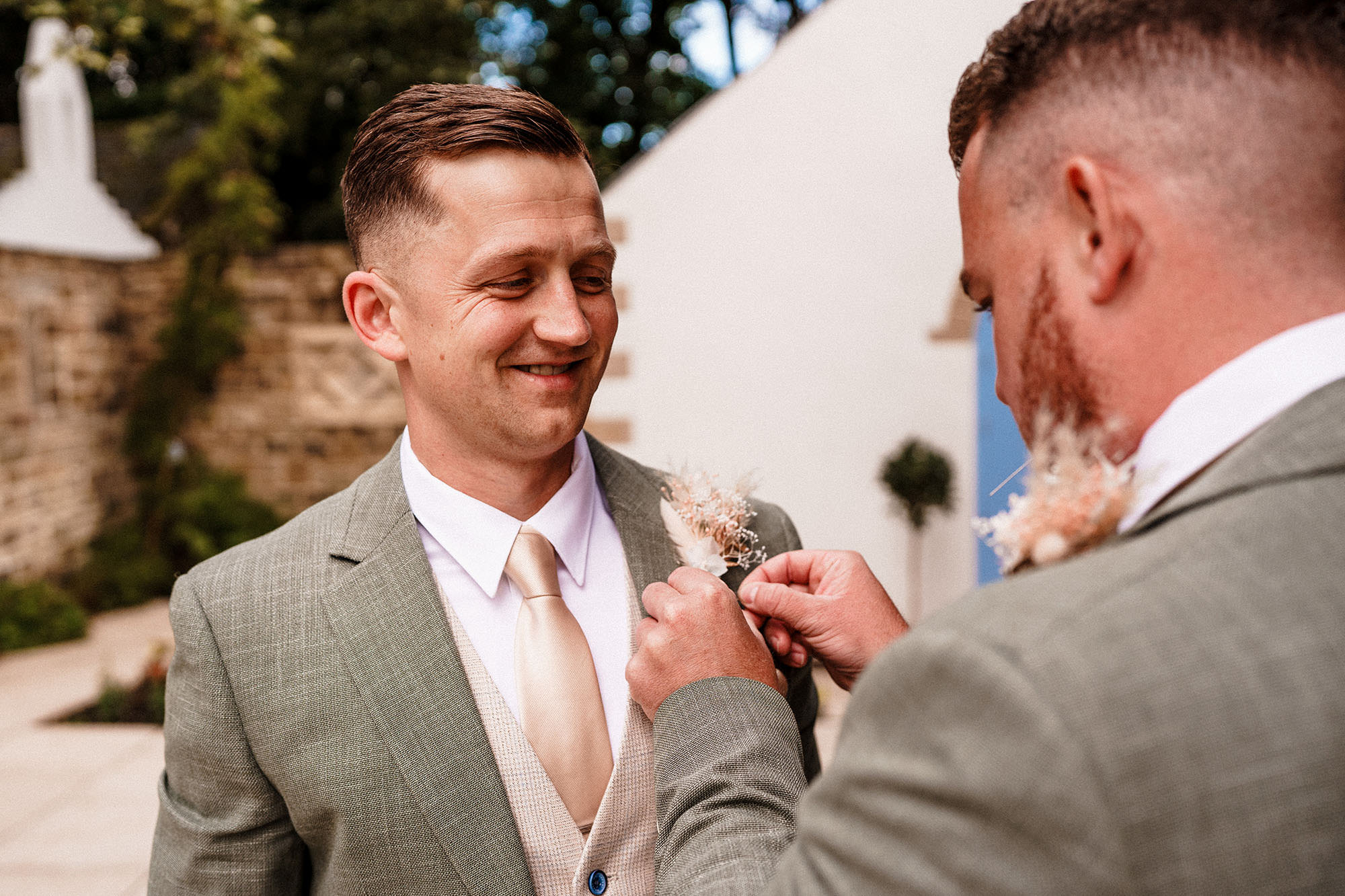 groom getting buttonhole put on by best man at wedding