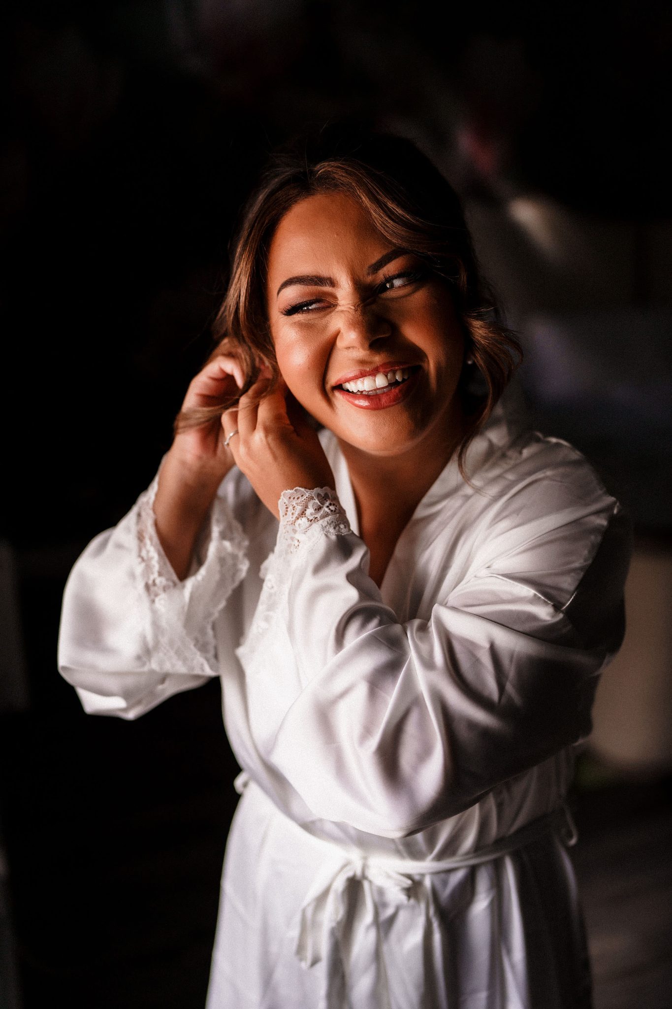 bride putting on earrings before her wedding at Woodhill hall