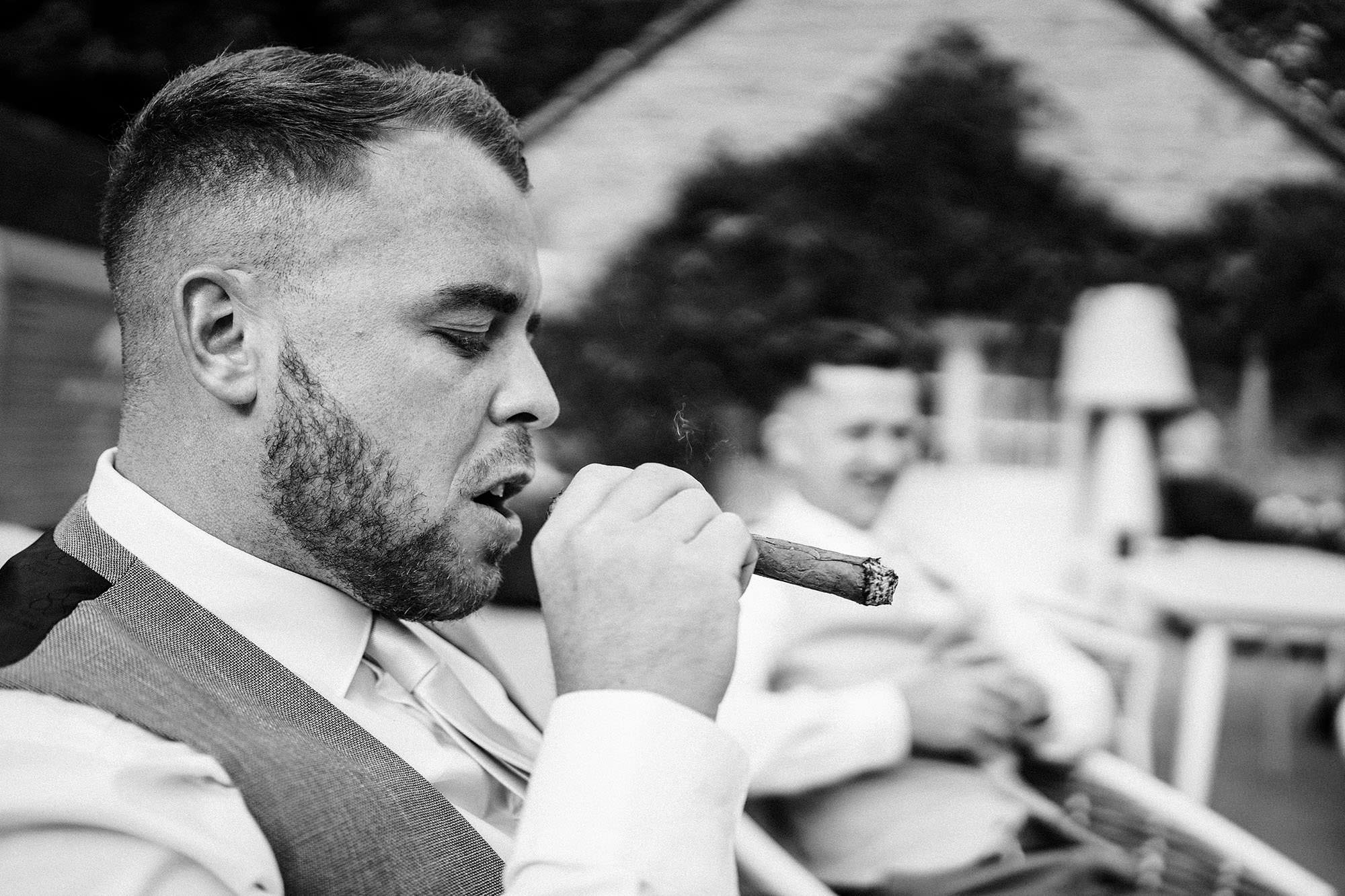 best man smokes cigar at wedding
