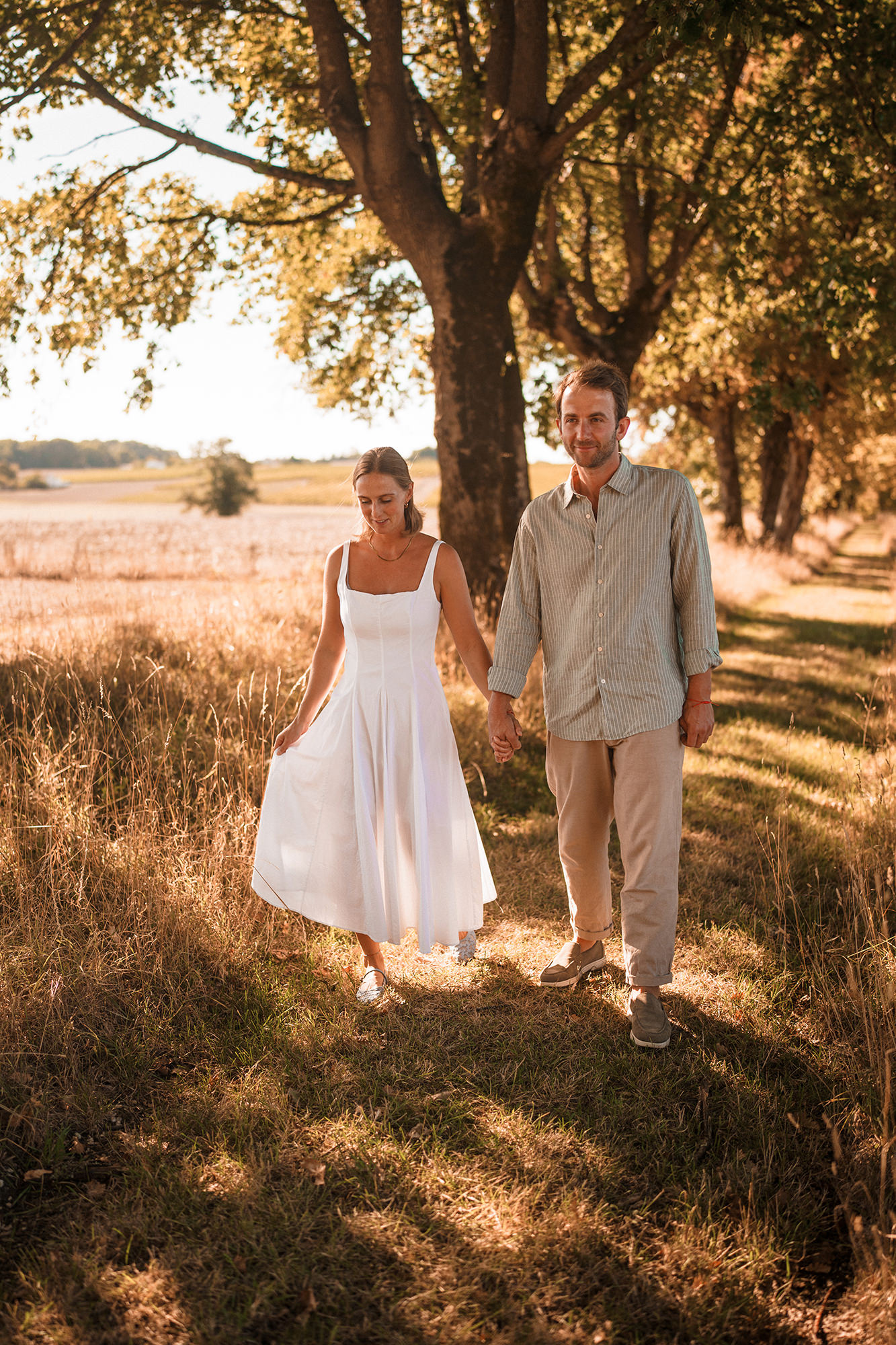 Anne-Sophie and Clément walking hand in hand through the French countryside