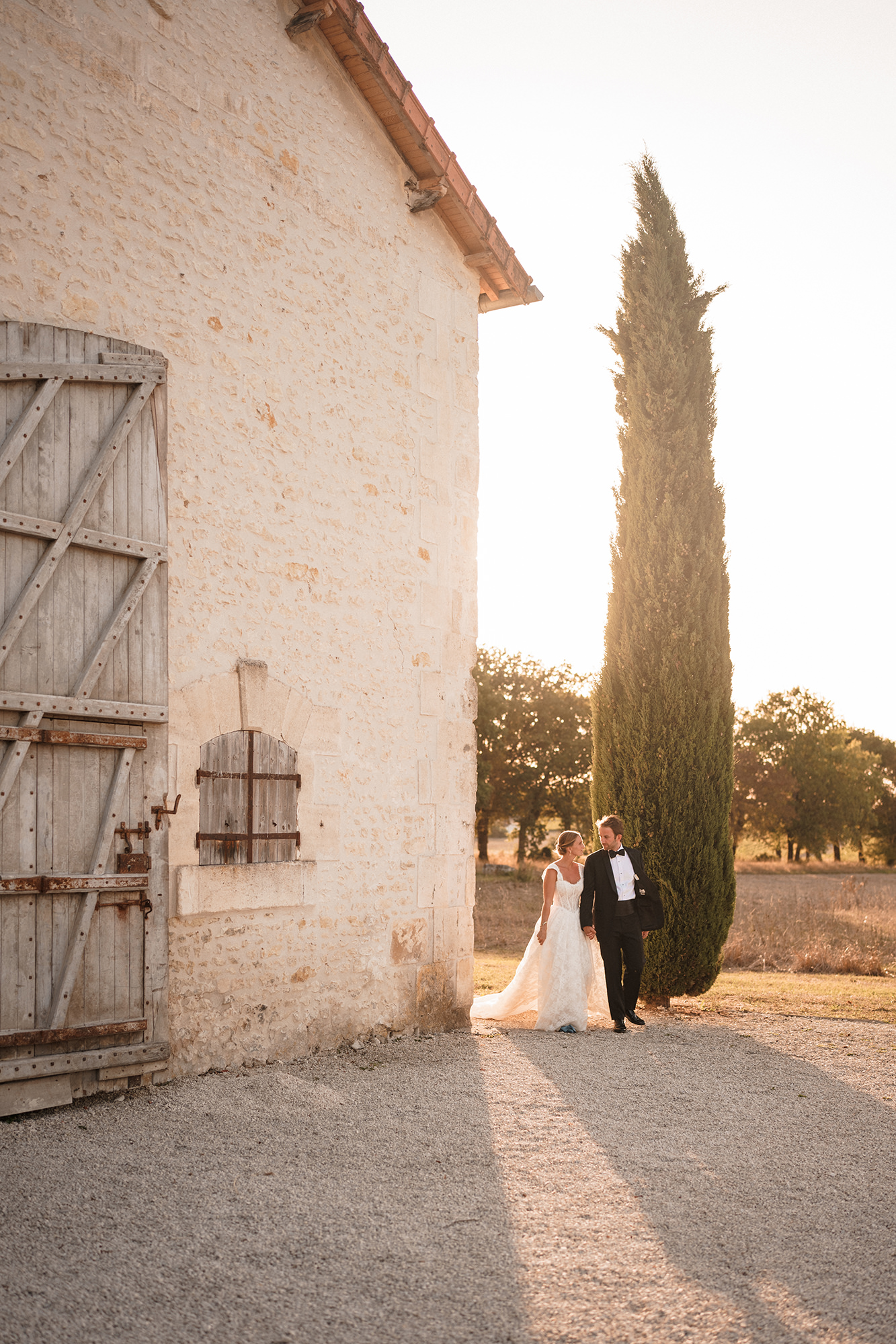 Anne-Sophie and Clément walking beside the stone buildings at La Cannonerie