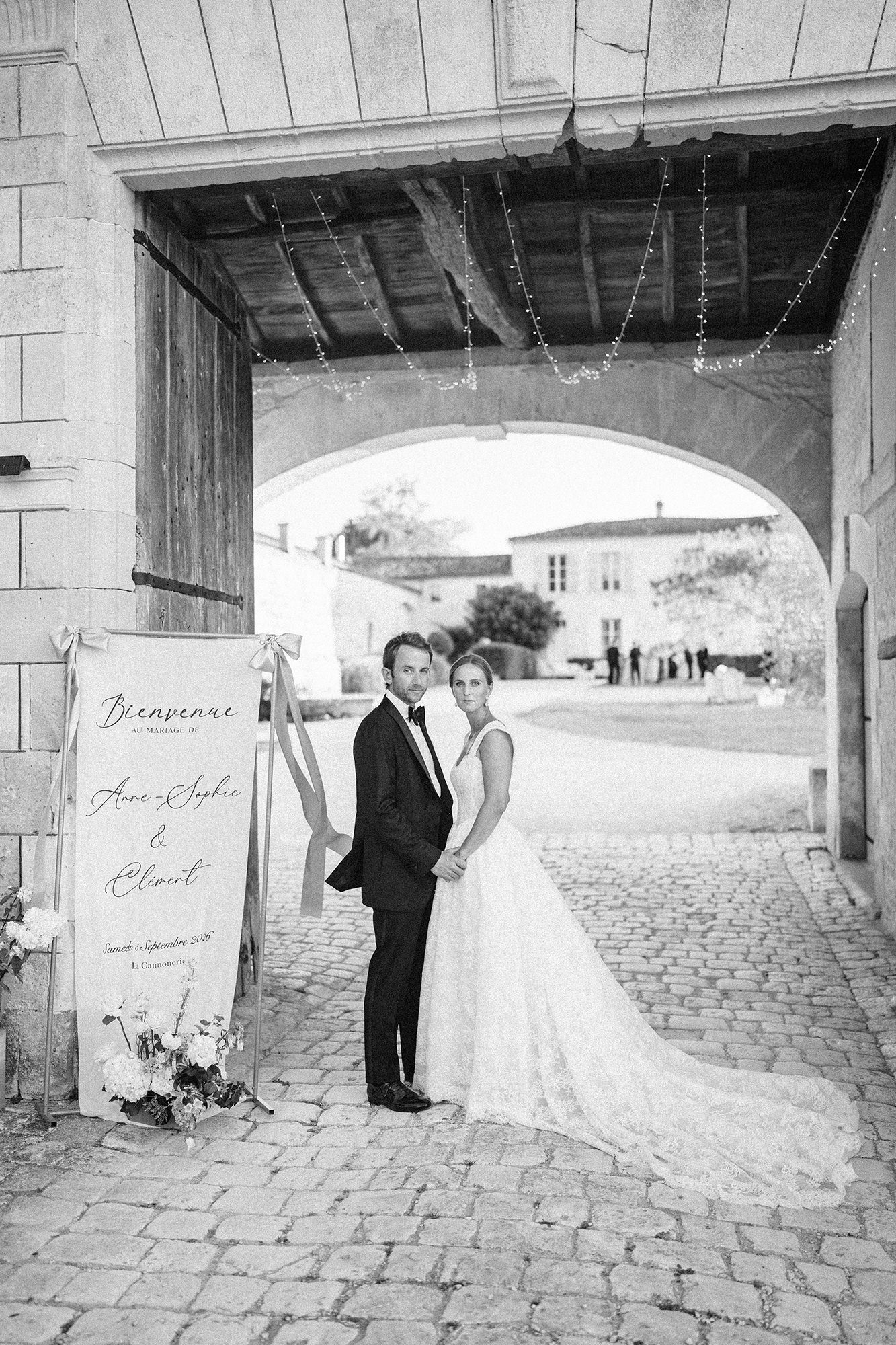 Black and white wedding portrait beneath an archway at La Cannonerie