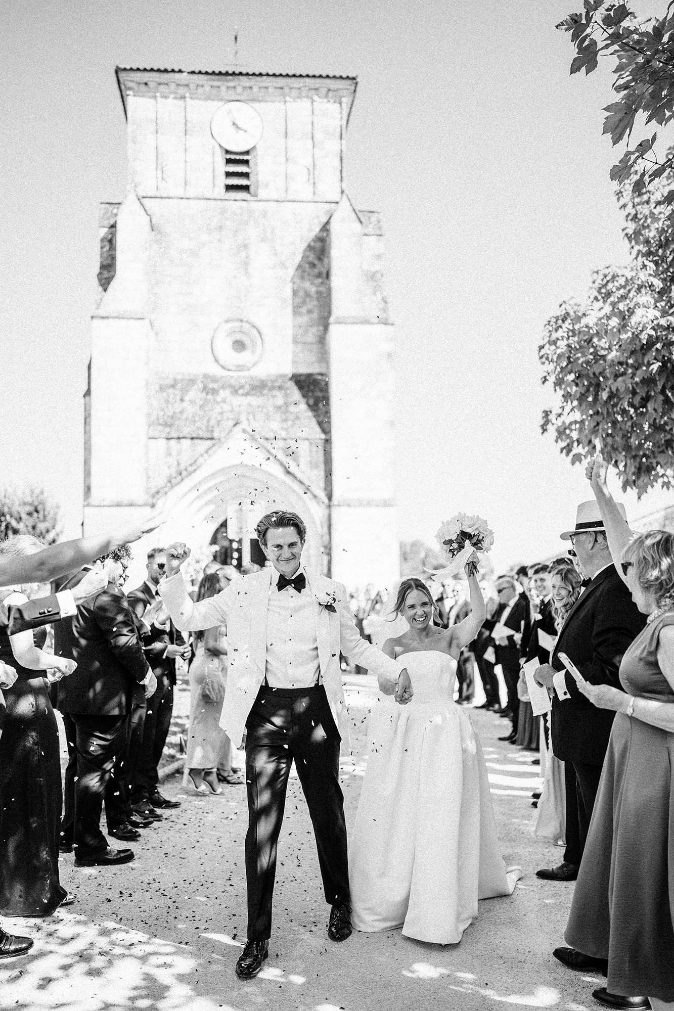 Newly married couple walking through confetti outside a church in France