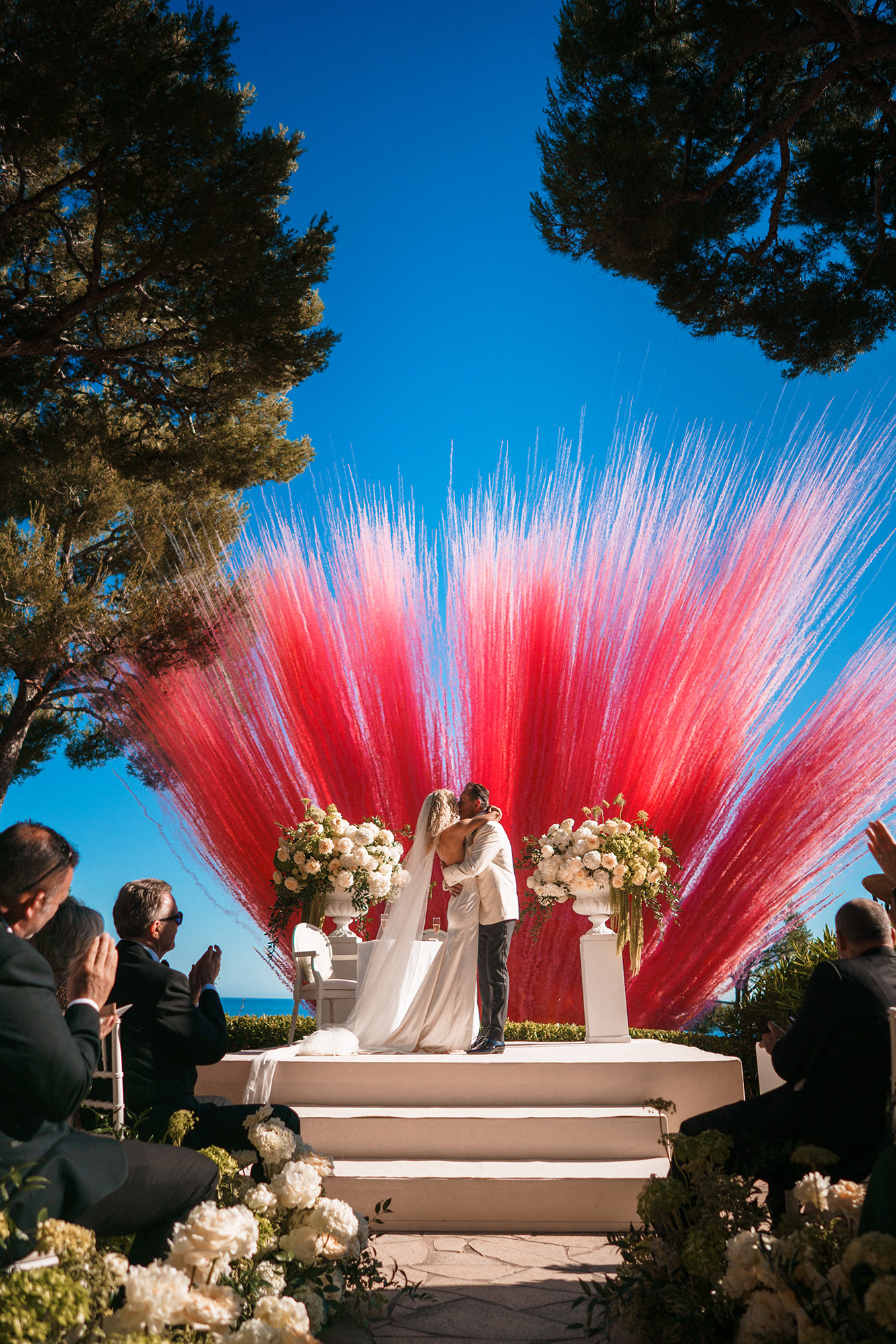 Couple kissing during a colourful outdoor wedding ceremony in France
