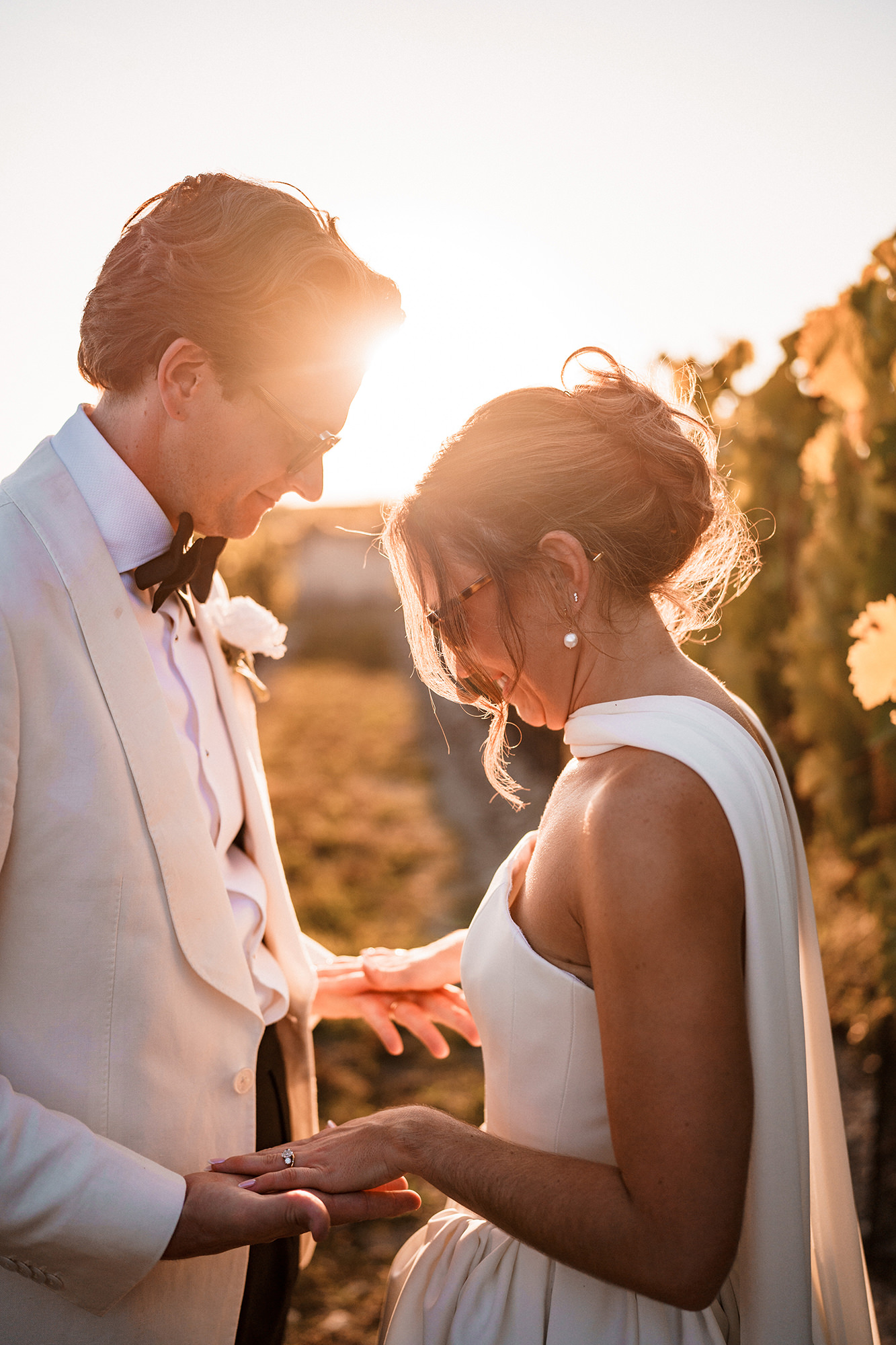 Wedding couple photographed in low evening sunlight beside vines in France