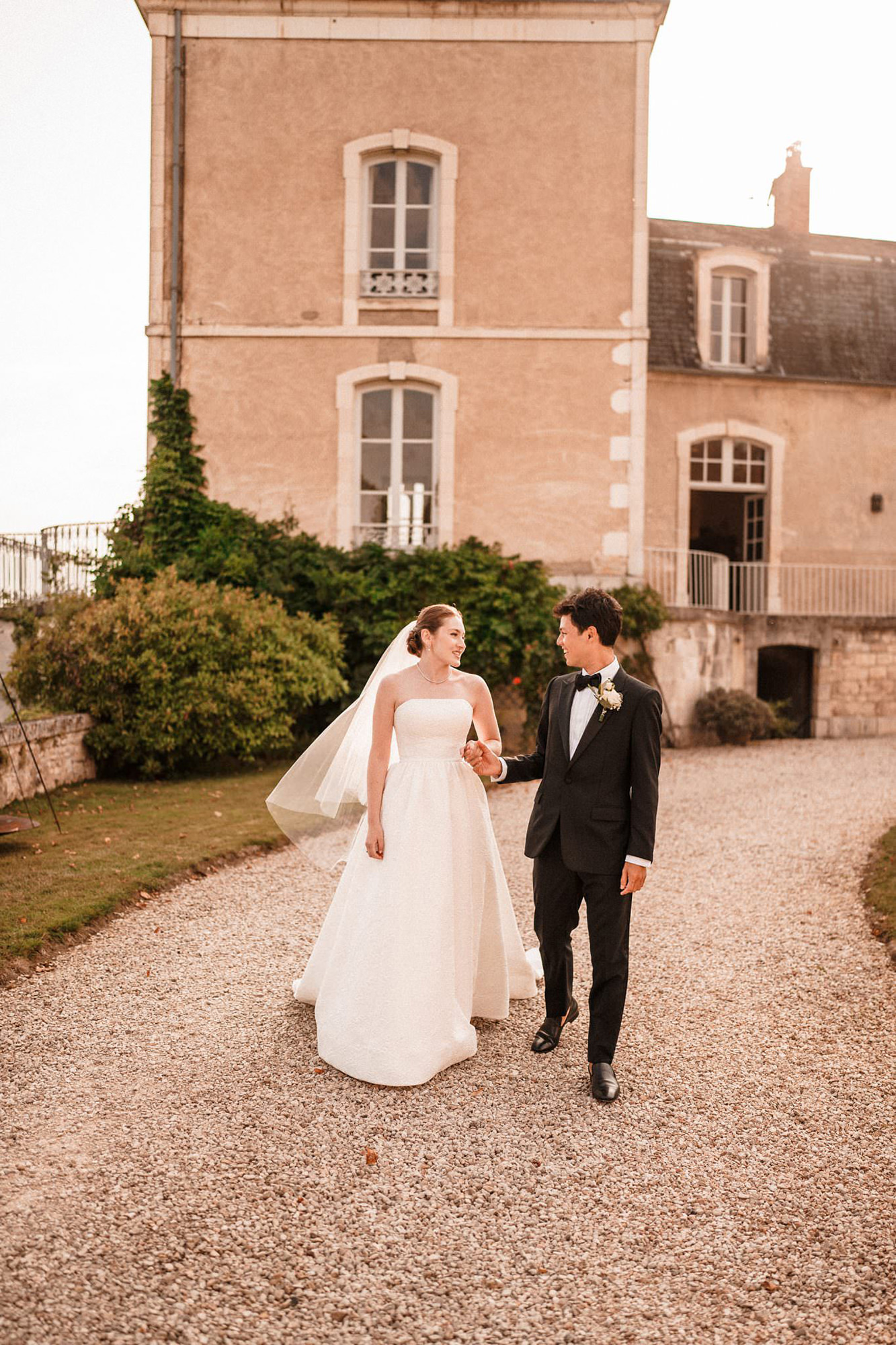 Bride and groom walking together outside a French château