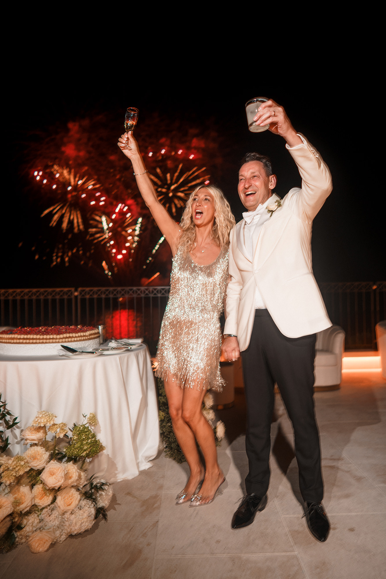 Newlyweds celebrating together with fireworks behind them