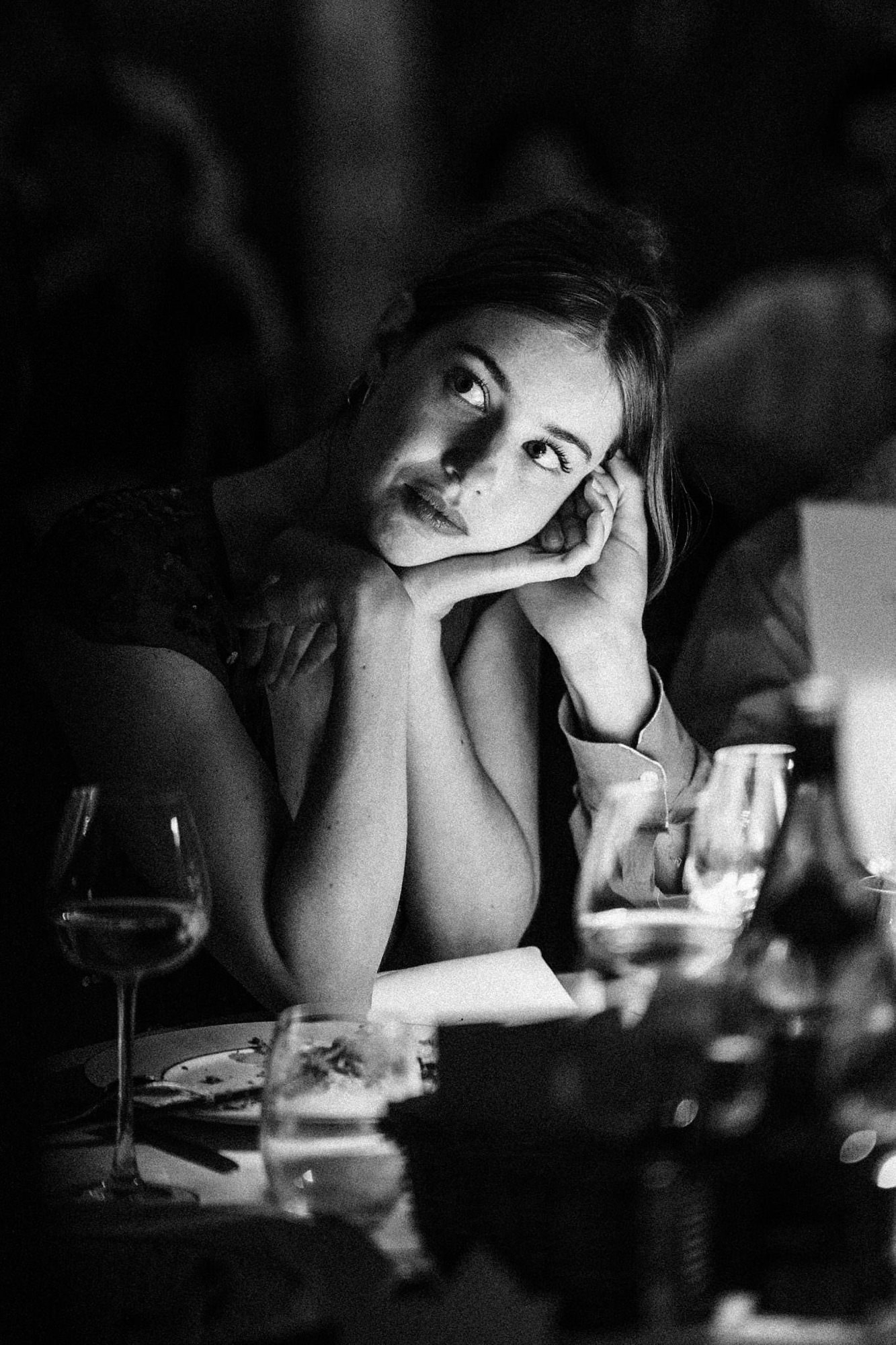 Candid black and white photograph of a wedding guest during dinner