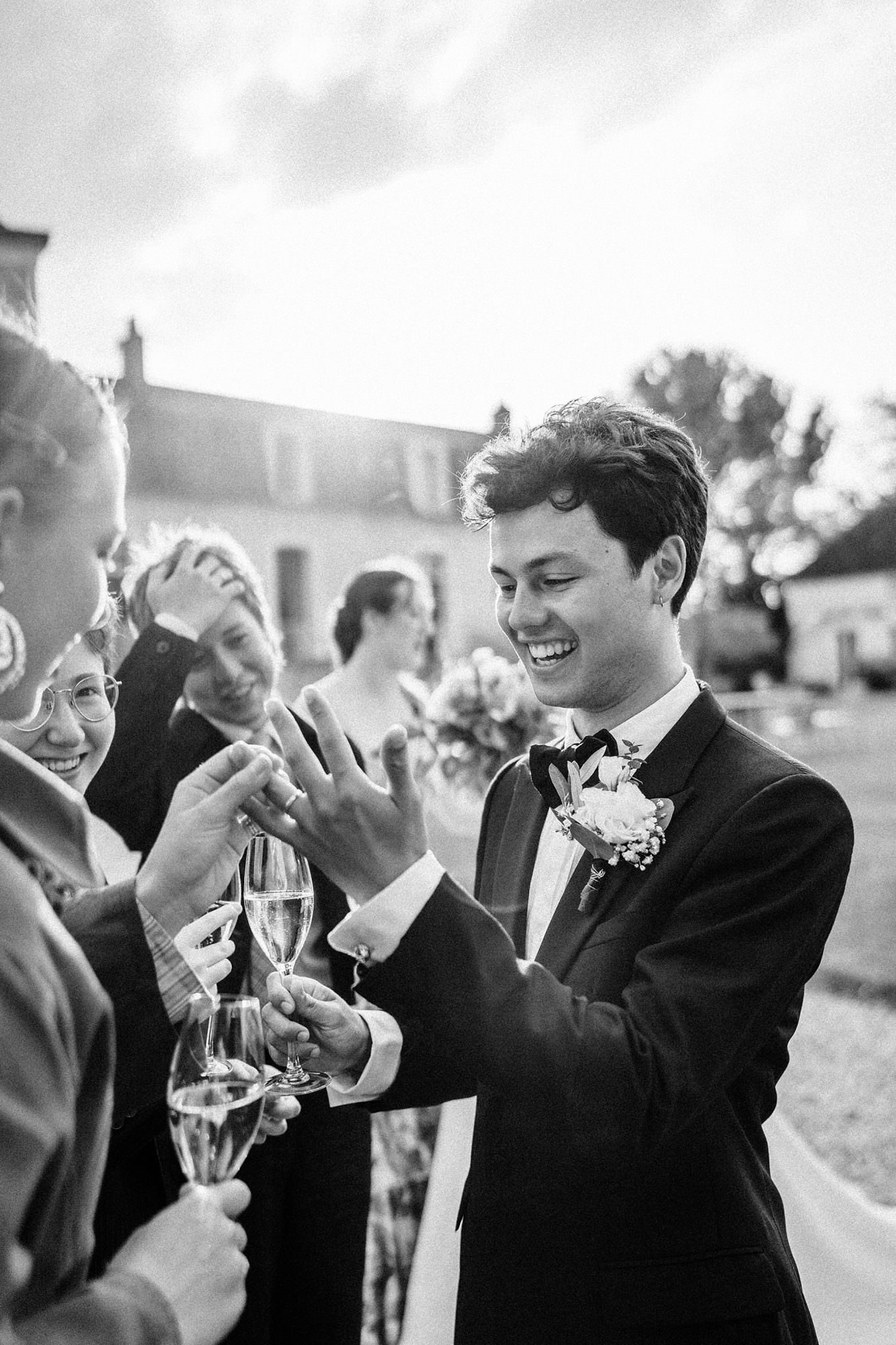 Groom laughing with guests over champagne at a French wedding