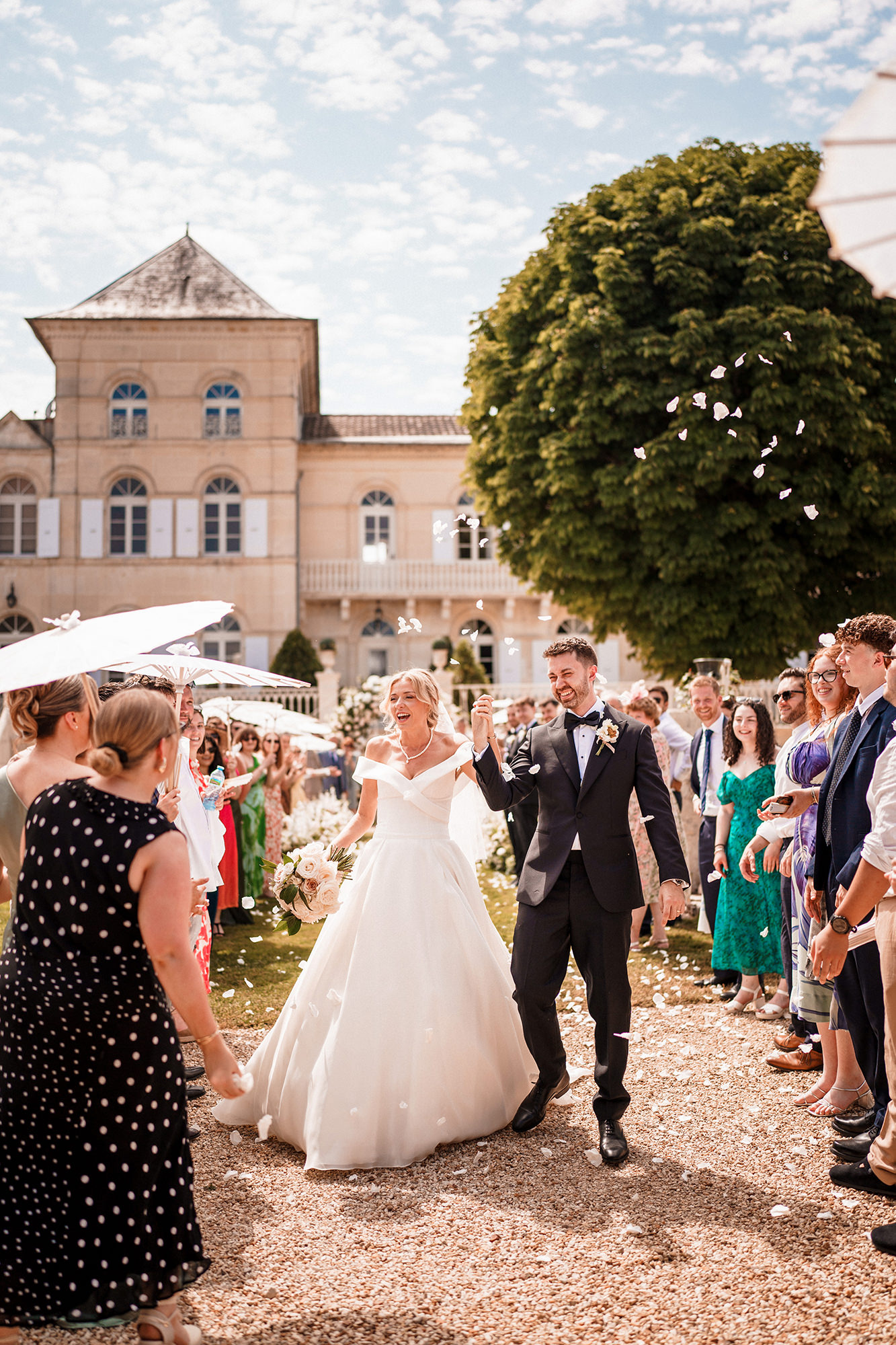 Newly married couple celebrating through confetti at a French château wedding