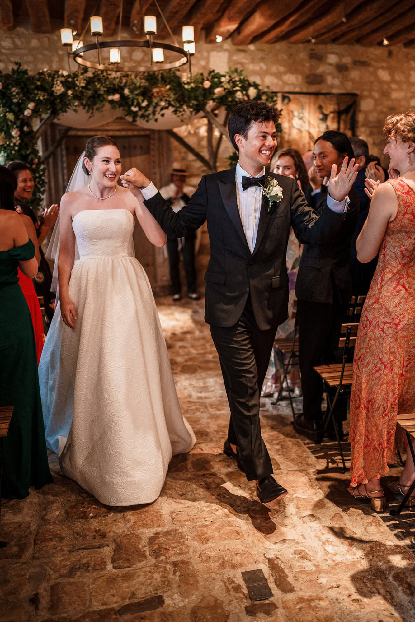 Newlyweds entering their wedding reception surrounded by guests in France