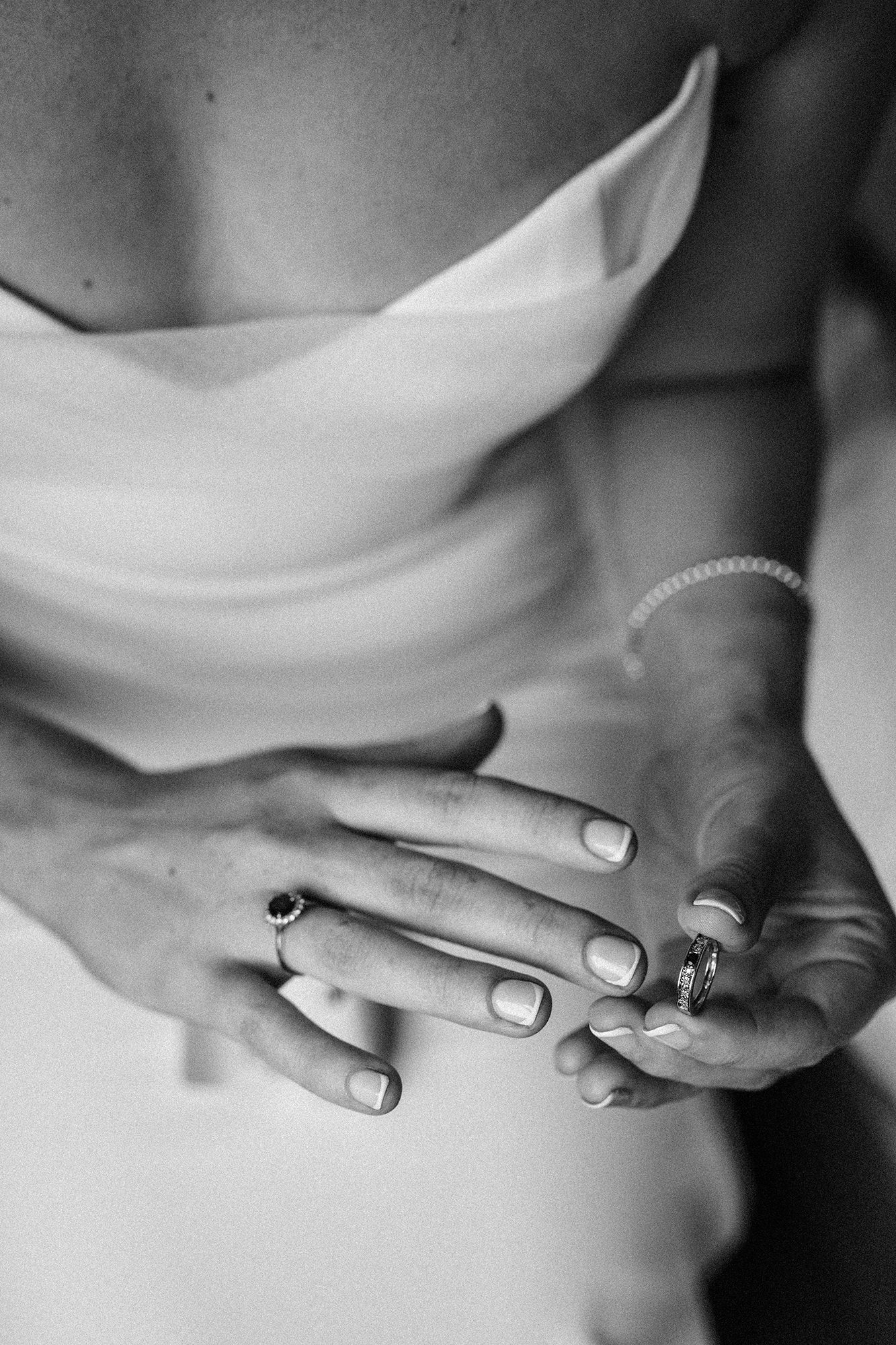 Black and white wedding photograph of a bride holding her rings