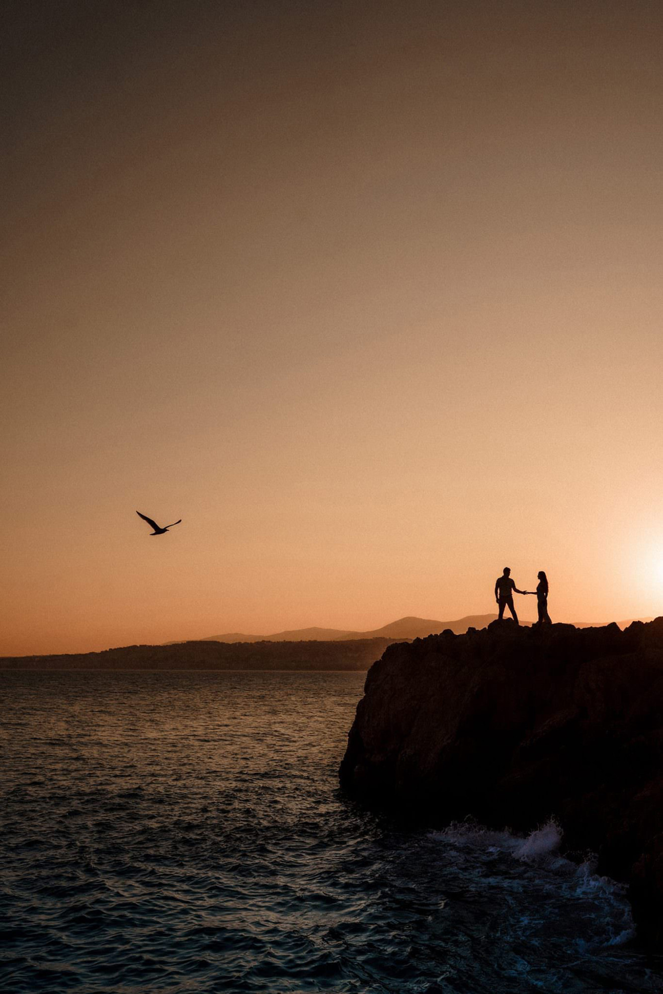Couple silhouetted on the rocks of the Côte d'Azur at sunset